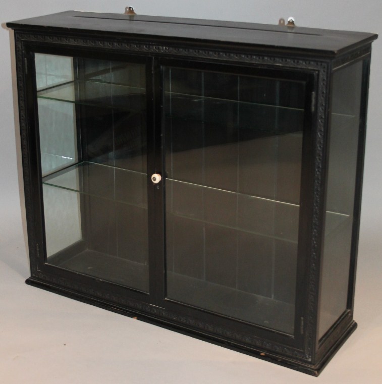 Appraisal: A thC ebonised hanging display cabinet the rectangular overhanging top