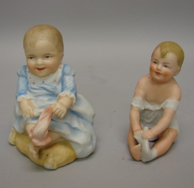 Appraisal: Pair of bisque sitting piano babies each pulling off a