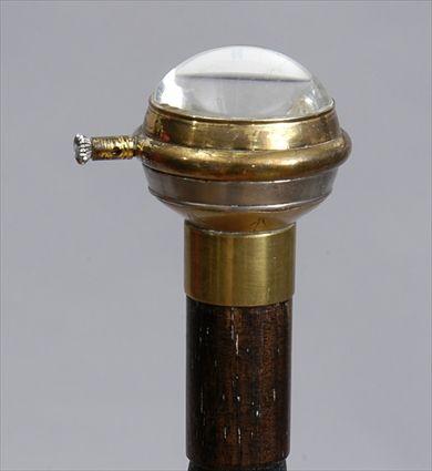 Appraisal: WATCH-HANDLED STAINED WOOD CANE The brass-mounted glass handle enclosing a