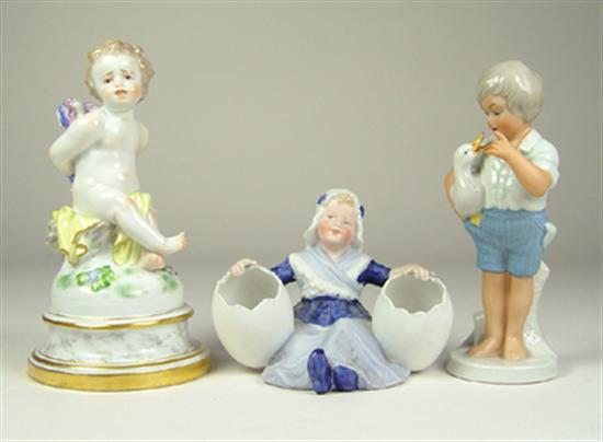 Appraisal: Three Porcelain Figurines Hand painted Cherub sitting on base High