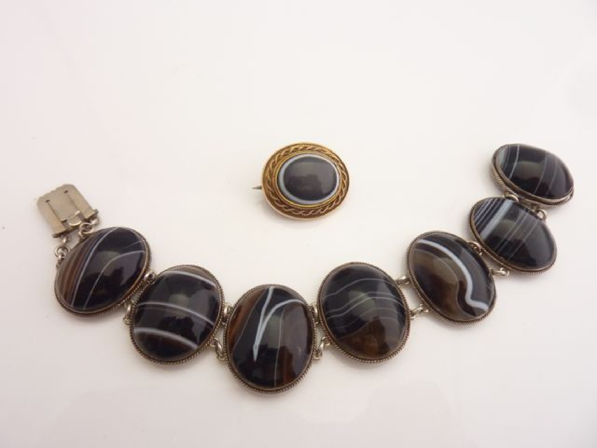 Appraisal: A banded onyx brooch in unmarked gold frame with rope-twist