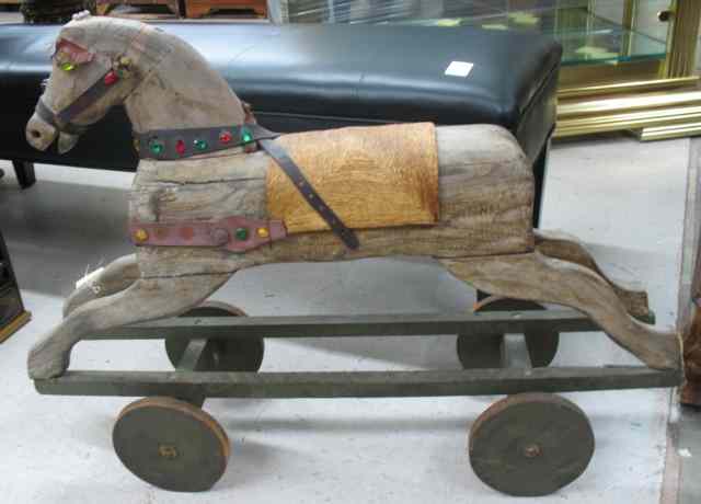 Appraisal: ANTIQUE WOOD HOBBY HORSE ON WHEELS the unpainted wood horse