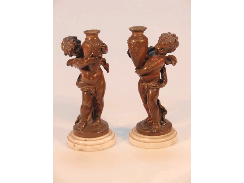 Appraisal: A pair of patinated bronze Putti clasping amphora on white