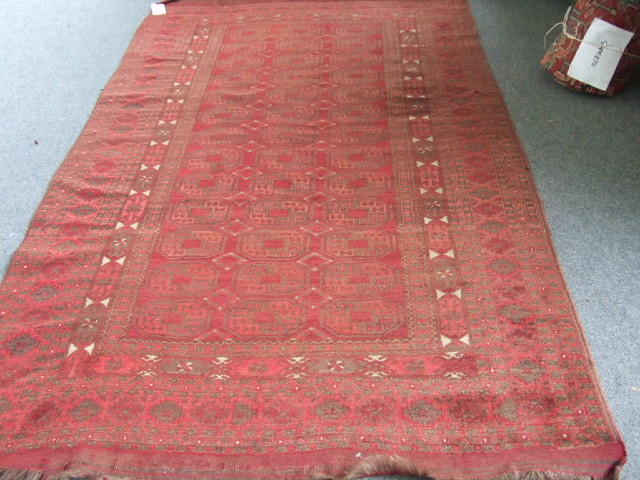 Appraisal: An Afghan carpet the madder field with three columns of