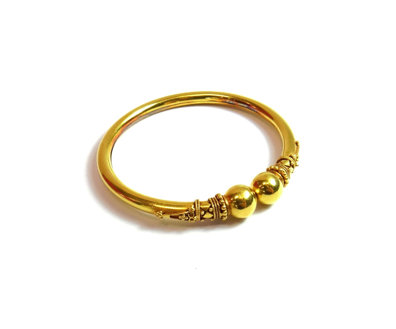 Appraisal: A gold bangle of sprung circular form with applied bead