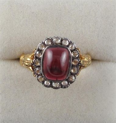 Appraisal: A garnet and diamond cluster ring The cabochon garnet is