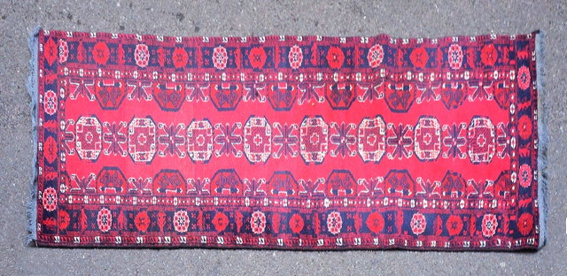 Appraisal: AN AFGHAN BELOUCH RED GROUND RUNNER decorated a continuing row