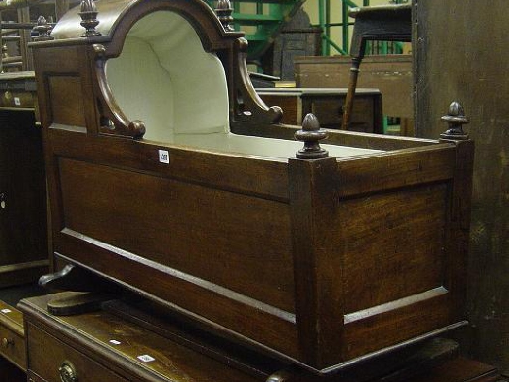 Appraisal: A Victorian mahogany cradle with panelled frame and arched canopy