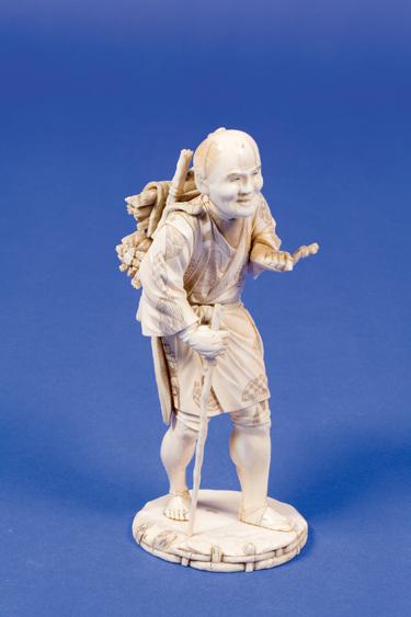 Appraisal: A JAPANESE IVORY OKIMONO of an agricultural worker carrying bundles