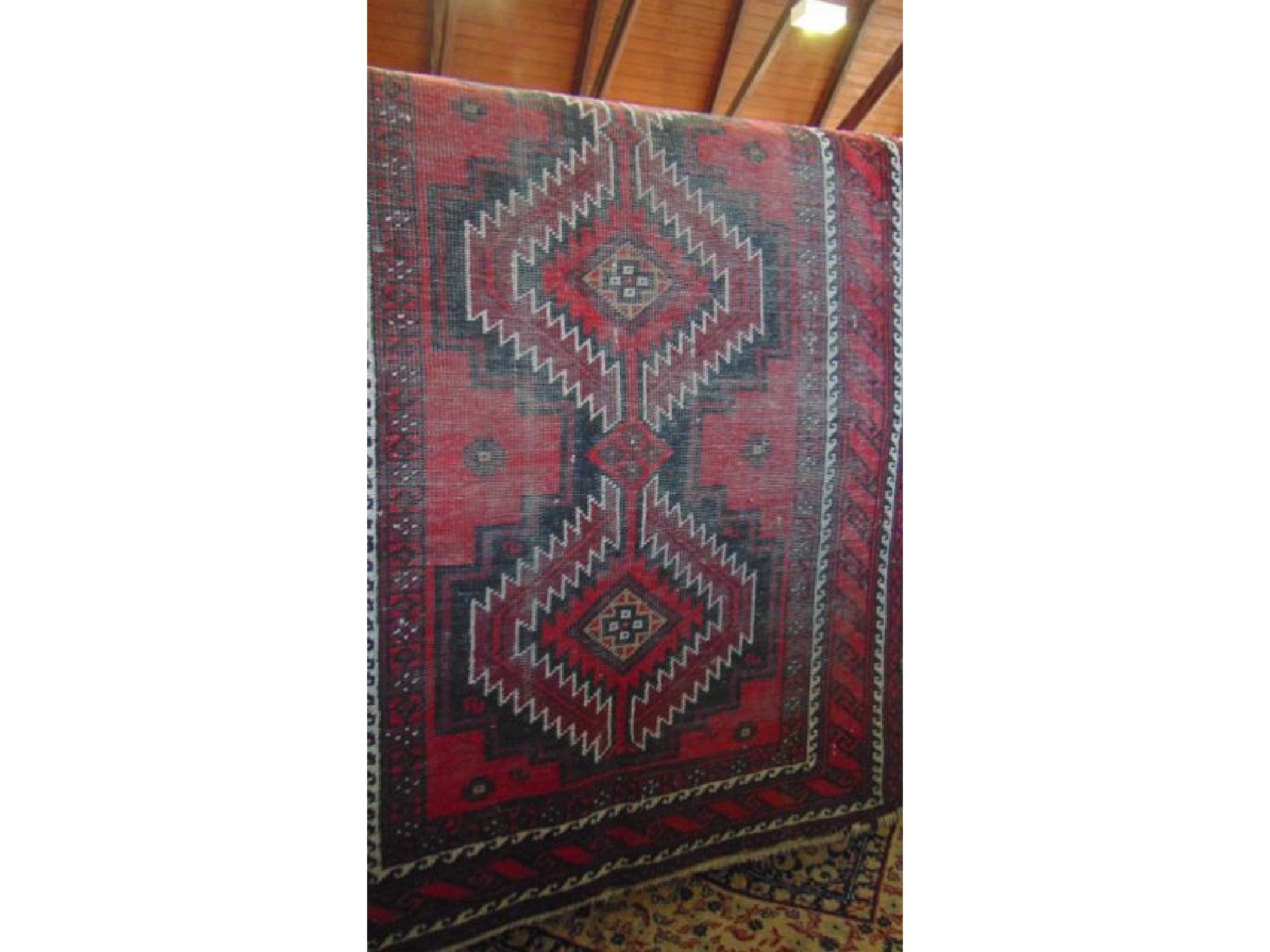 Appraisal: An eastern wool work rug with geometric medallion centre in