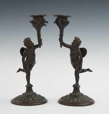 Appraisal: A Pair of Bronze Cherub Candlesticks Cast bronze with applied