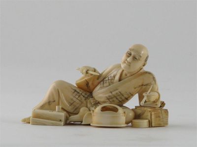 Appraisal: A Japanese ivory carving of a reclining man holding a