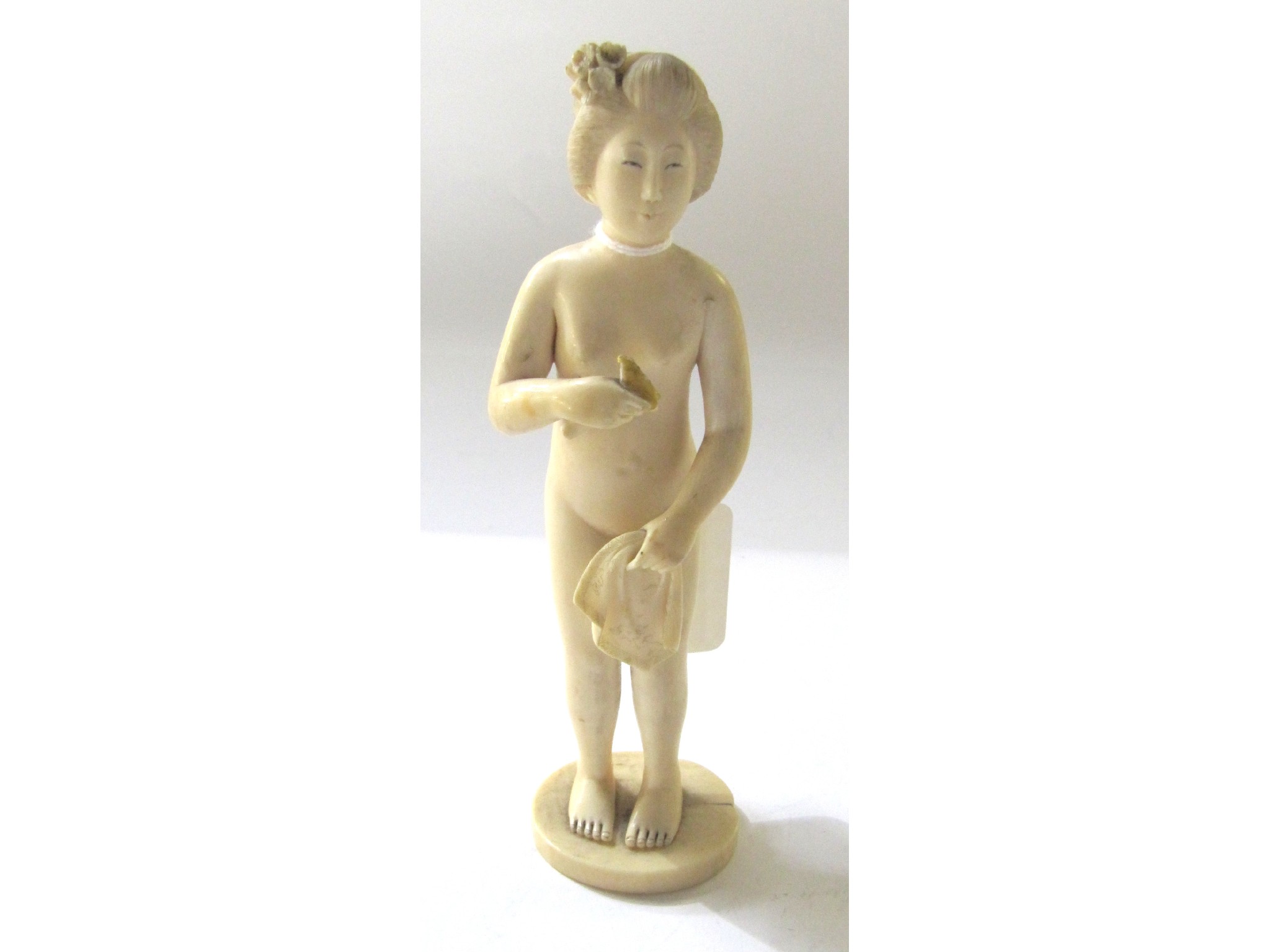 Appraisal: A Japanese carved ivory okimono of a lady bathing some