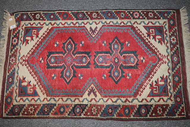 Appraisal: A PAKISTAN RED GROUND RUG with two central star designs