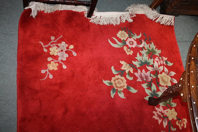 Appraisal: A CHINESE RED GROUND RUG with flower sprays to each