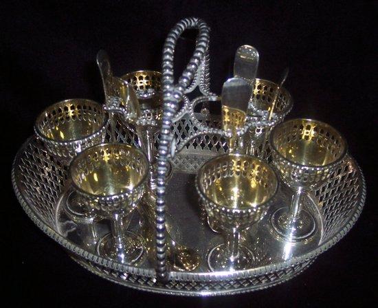 Appraisal: An oval egg cup stand with beaded cross over handle