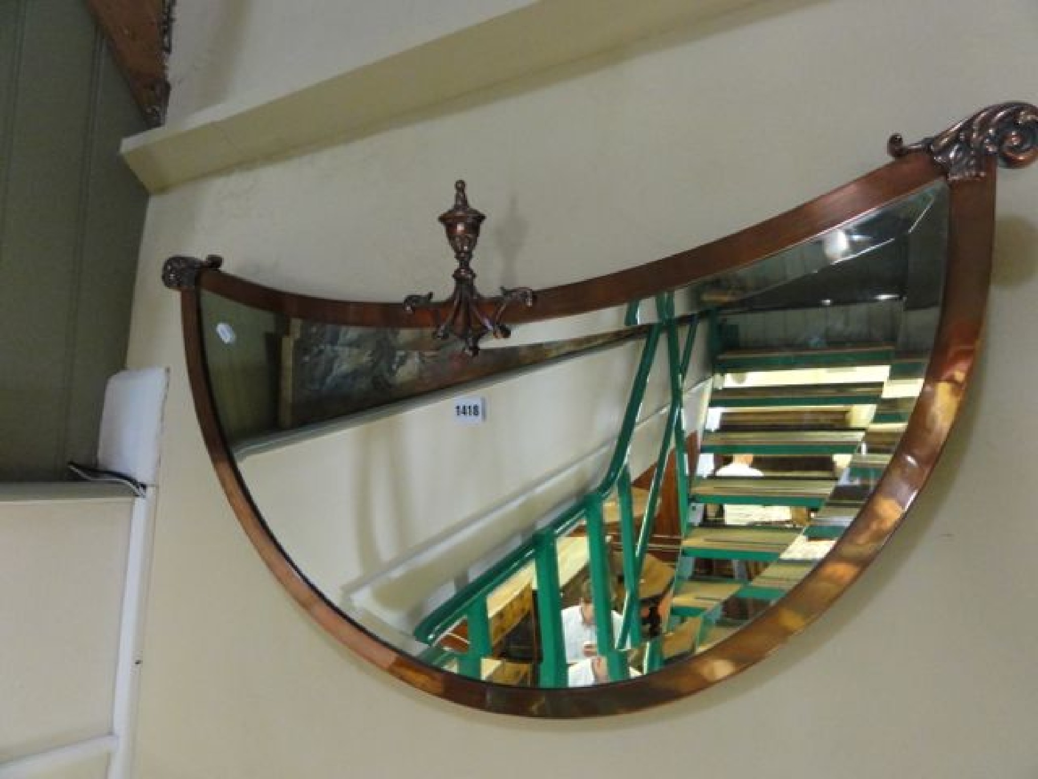 Appraisal: An unusual Edwardian anodised copper framed crescent shaped wall mirror