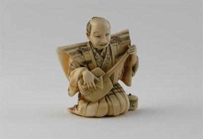 Appraisal: A Japanese ivory carving of a musician kneeling whilst playing