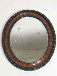 Appraisal: An oval bevelled mirror the wooden frame with egg moulding