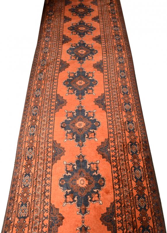 Appraisal: A PERSIAN FLOOR RUNNERwith repeating medallions on a terracotta ground