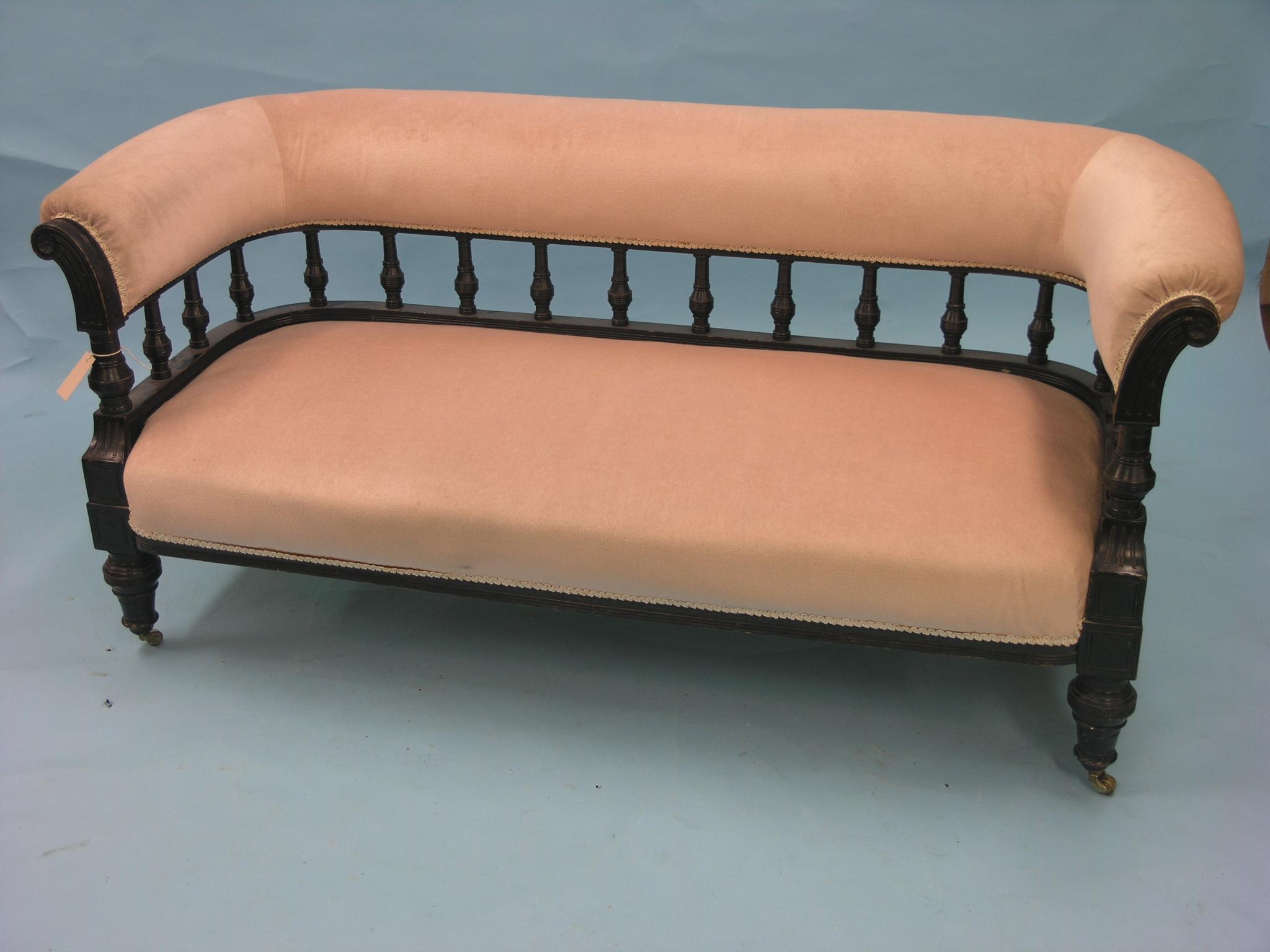 Appraisal: A late Victorian ebonised mahogany settee twin-seater with turned spindle