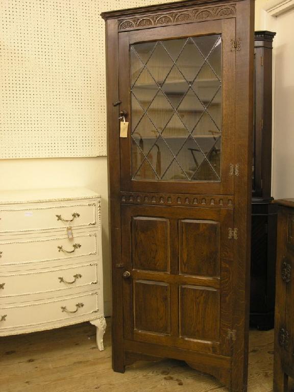 Appraisal: A reproduction dark oak corner cabinet floor standing with leaded