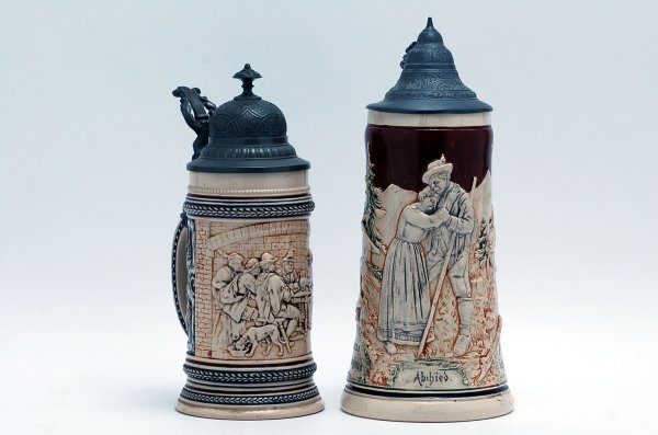 Appraisal: Two steins with raised figural scenes and ornate pewter lids