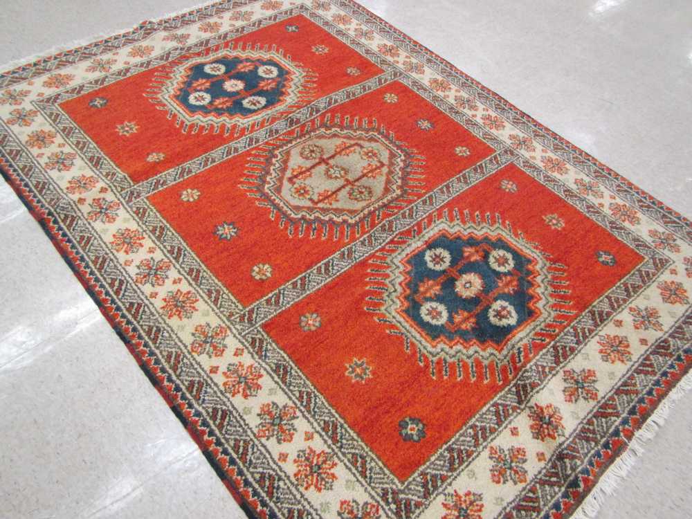 Appraisal: HAND KNOTTED ORIENTAL CARPET Indo-Caucasian featuring three geometric latch-hook medallions