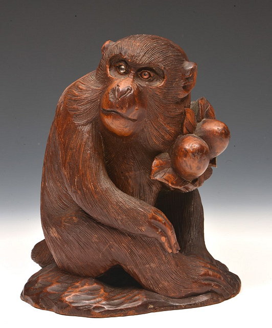 Appraisal: A JAPANESE CARVED WOOD SEATED MONKEY holding two berries signed