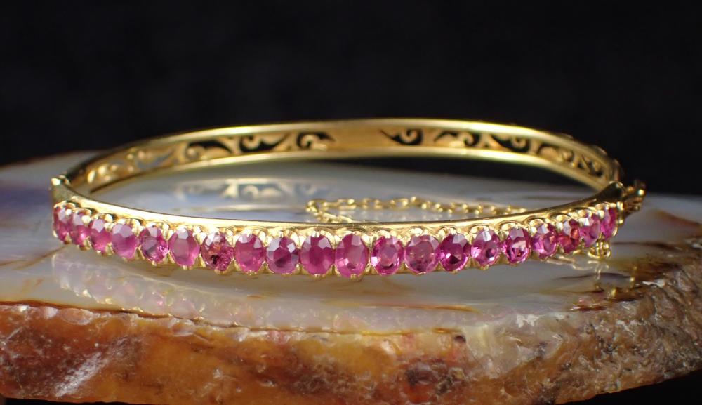 Appraisal: PINK SAPPHIRE AND EIGHTEEN KARAT GOLD BANGLE The oval hinged