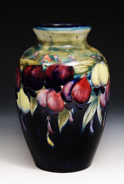 Appraisal: A Moorcroft vasedecorated with wisteria and pomegranate impressed Cobridge factory