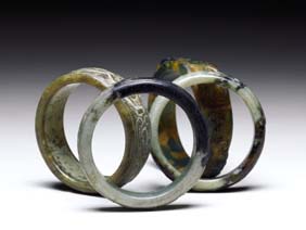 Appraisal: FOUR JADE AND HARDSTONE BANGLES Four Chinese carved jade and