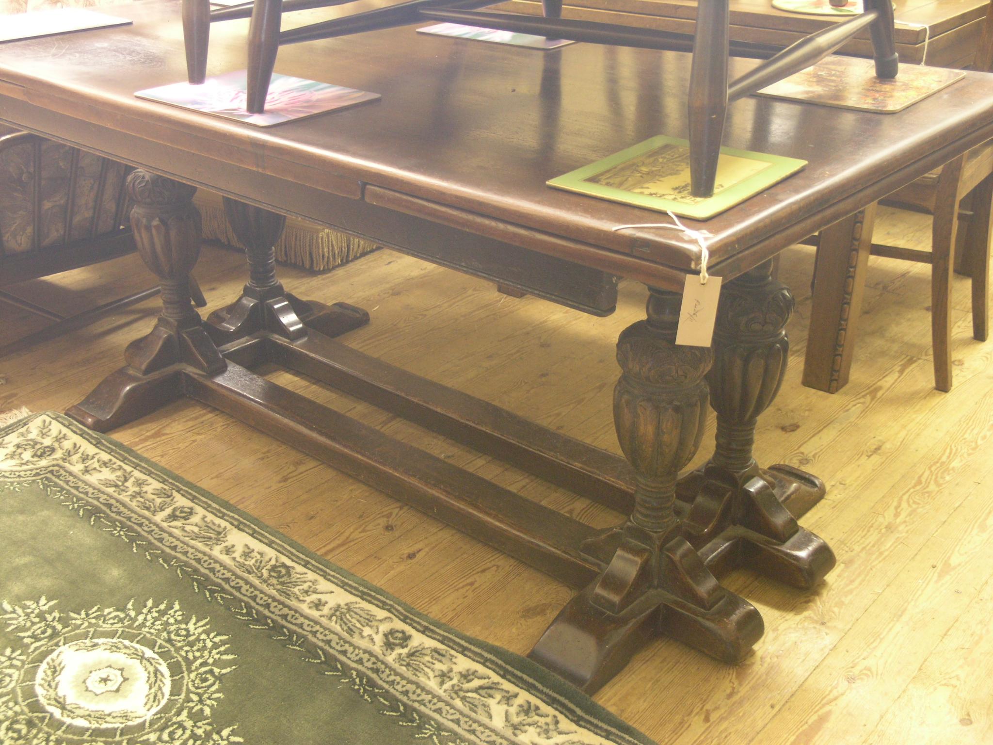 Appraisal: A dark oak draw-leaf dining table on twin carved end