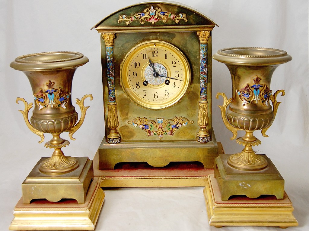 Appraisal: A French clock garniture enamel decorated brass cased with drum