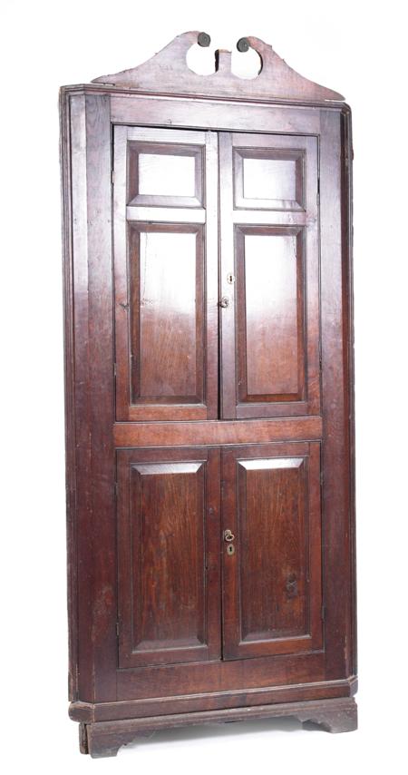 Appraisal: A George III oak standing corner cupboard the swan-neck pediment