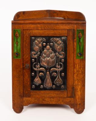 Appraisal: An Art Nouveau oak copper and enamel smokers corner cabinet