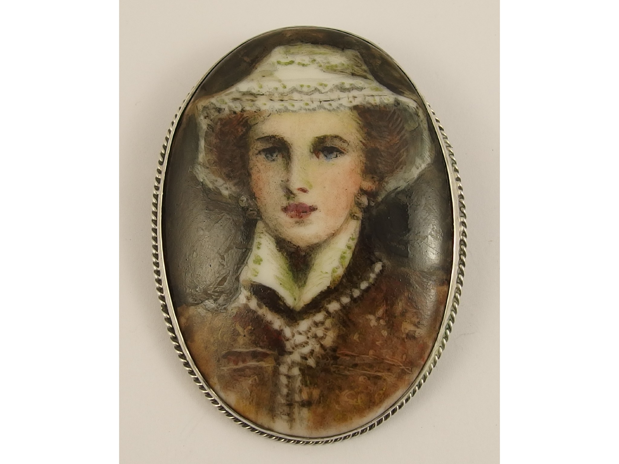 Appraisal: A white metal mounted brooch with a painted porcelain plaque