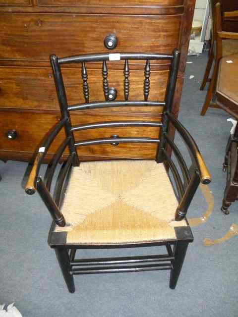 Appraisal: AN EBONISED RUSH SEATED OPEN ARMCHAIR from the Sussex range