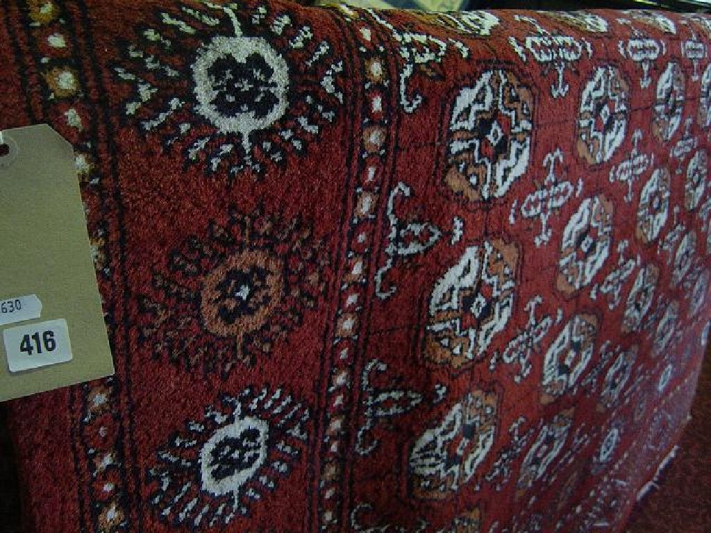 Appraisal: A red ground Eastern wool rug with repeating gul motifs