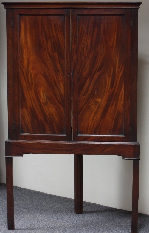 Appraisal: A George III mahogany corner cupboard with panelled doors on