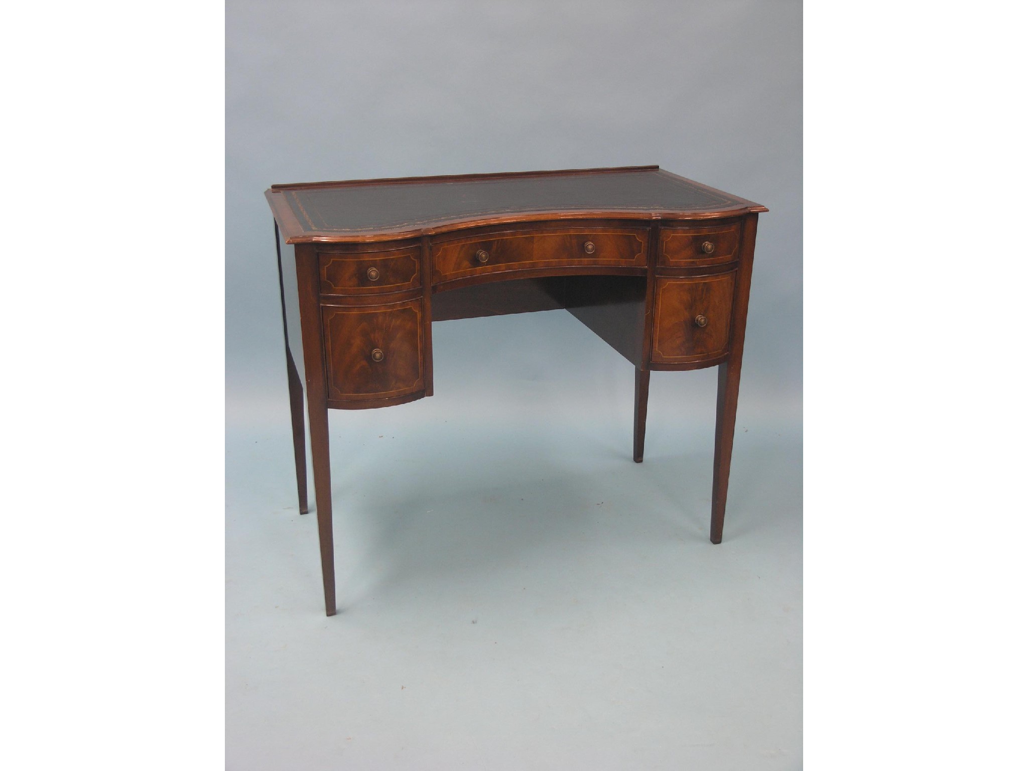 Appraisal: A reproduction inlaid mahogany writing table concave-shape inset gilt-tooled leather