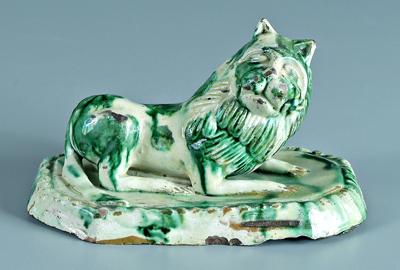 Appraisal: Earthenware recumbent lion copper splashed glaze cartouche shaped platform probably