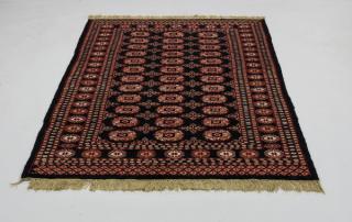 Appraisal: Hand-knotted Boukhara rug executed in wool centering three rows of