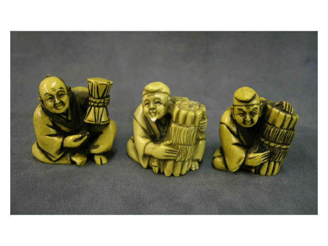 Appraisal: Three stained ivory netsuke including one depicting man holding a