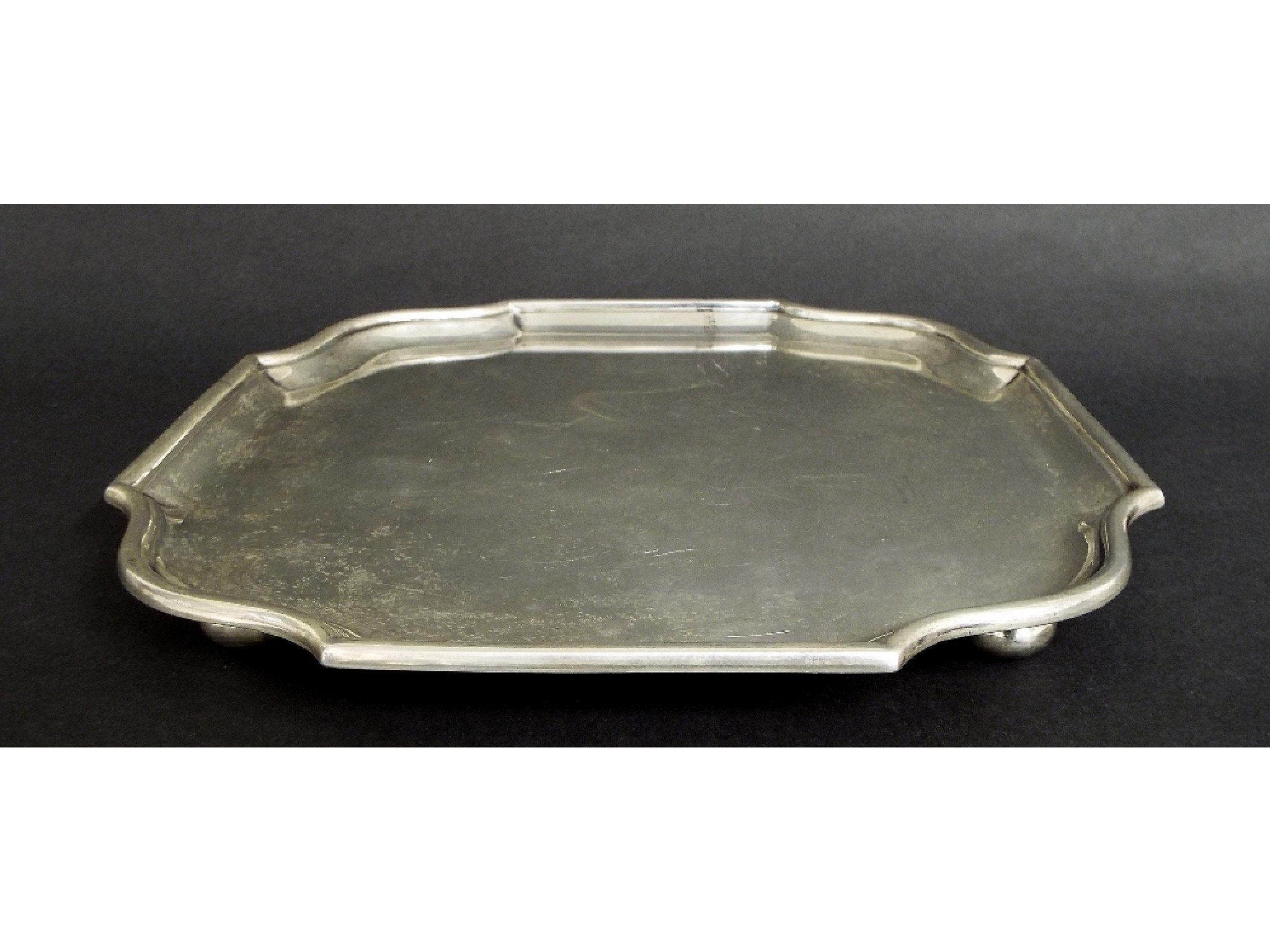 Appraisal: Edwardian silver square serpentine salver upon four bun feet maker