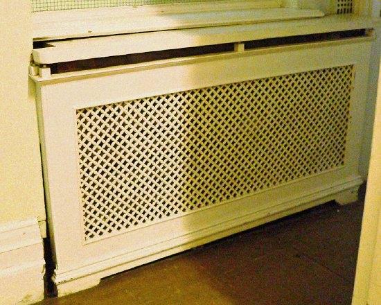 Appraisal: A single pierced cast radiator surround with wooden top on