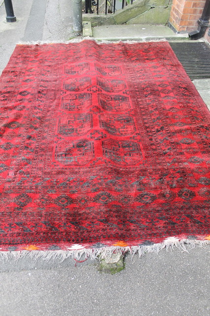 Appraisal: AN EASTERN RED GROUND WOOL RUG with geometric decoration x