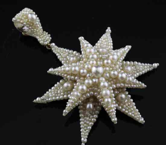 Appraisal: A graduated pearl starburst pendant with gold mounts and mother