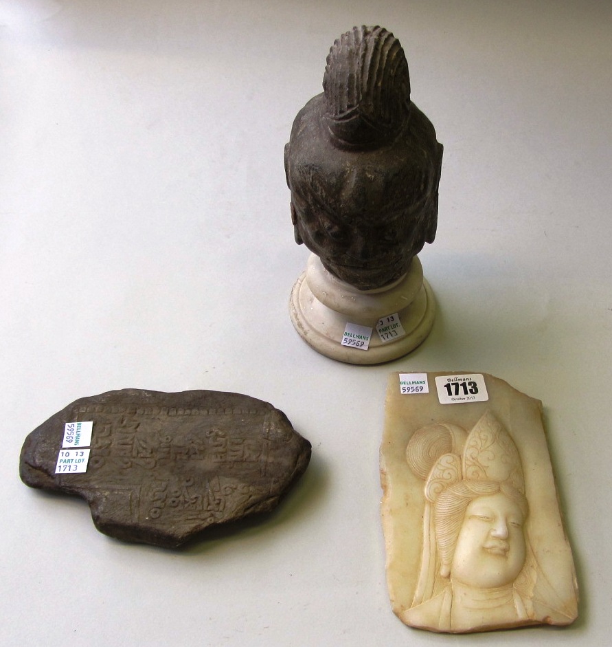 Appraisal: A South East Asian stone head on a marble socle