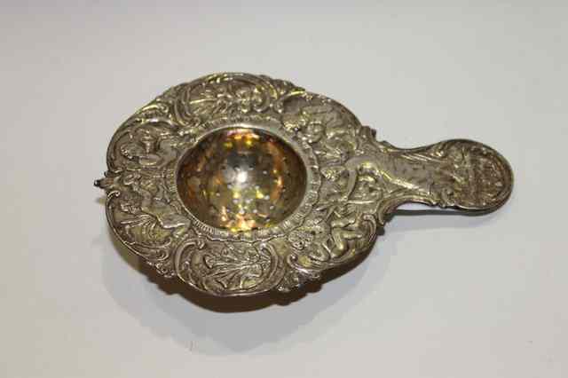 Appraisal: A CONTINENTAL SILVER TEA STRAINER with relief cherub and floral